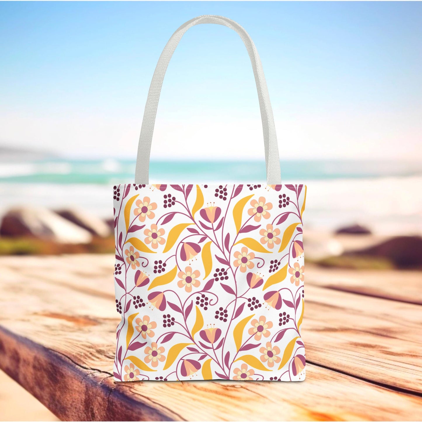 Golden Paisley Floral Tote Bag on weathered wooden surface, showcasing a vibrant floral vine pattern in warm tones, perfect for joyful summer outings. Durable polyester with reinforced handles and boxed corners for spacious utility.