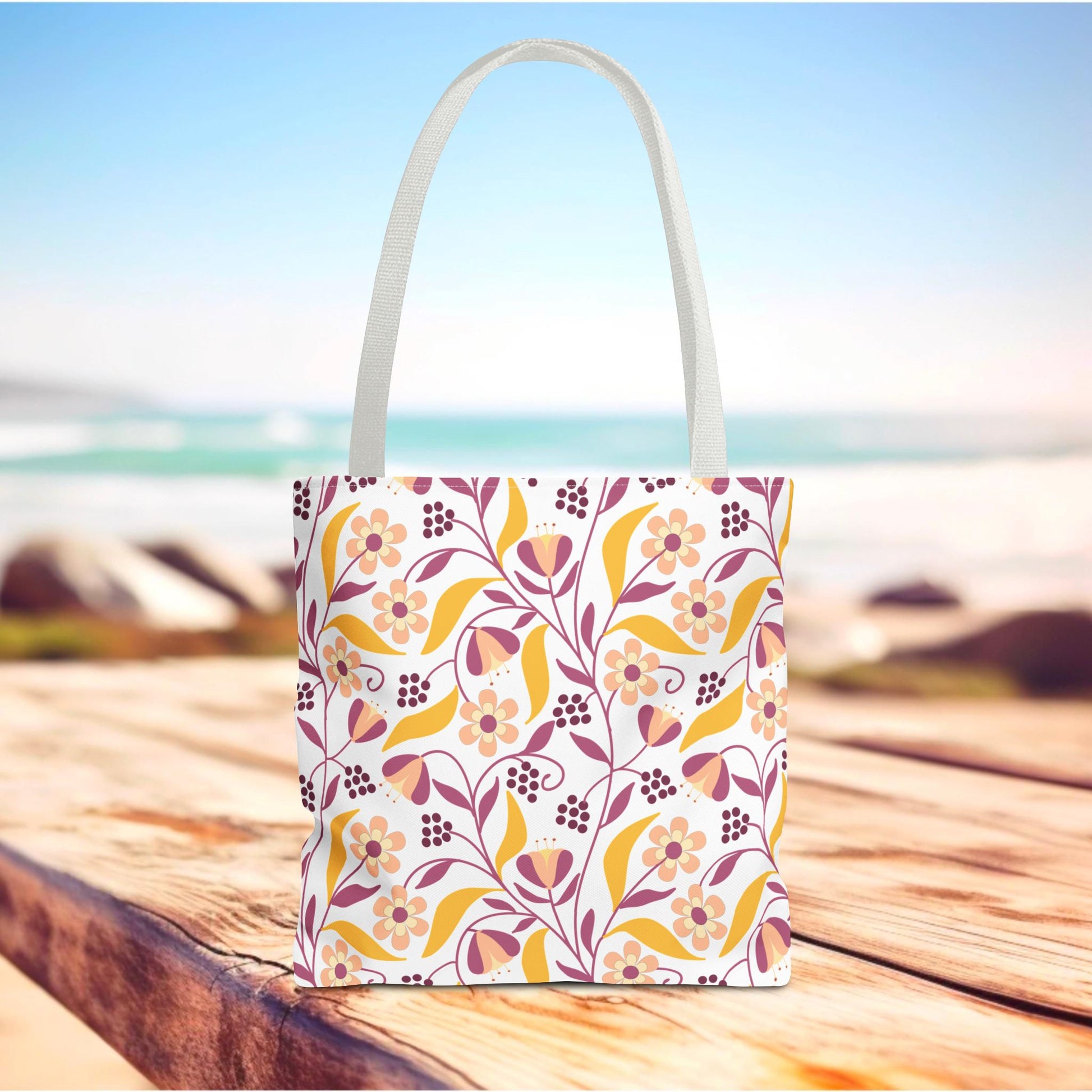 Golden Paisley Floral Tote Bag on weathered wooden surface, showcasing a vibrant floral vine pattern in warm tones, perfect for joyful summer outings. Durable polyester with reinforced handles and boxed corners for spacious utility.