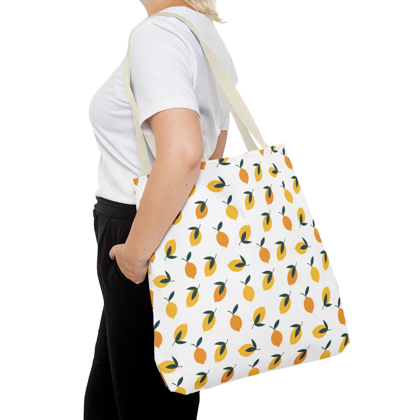 Person wearing a white T-shirt and black pants with a Lemon Drop Toss Tote Bag, featuring vibrant lemons and green leaves, perfect for summer outings, embodying FireBrook Essentials' uplifting style.