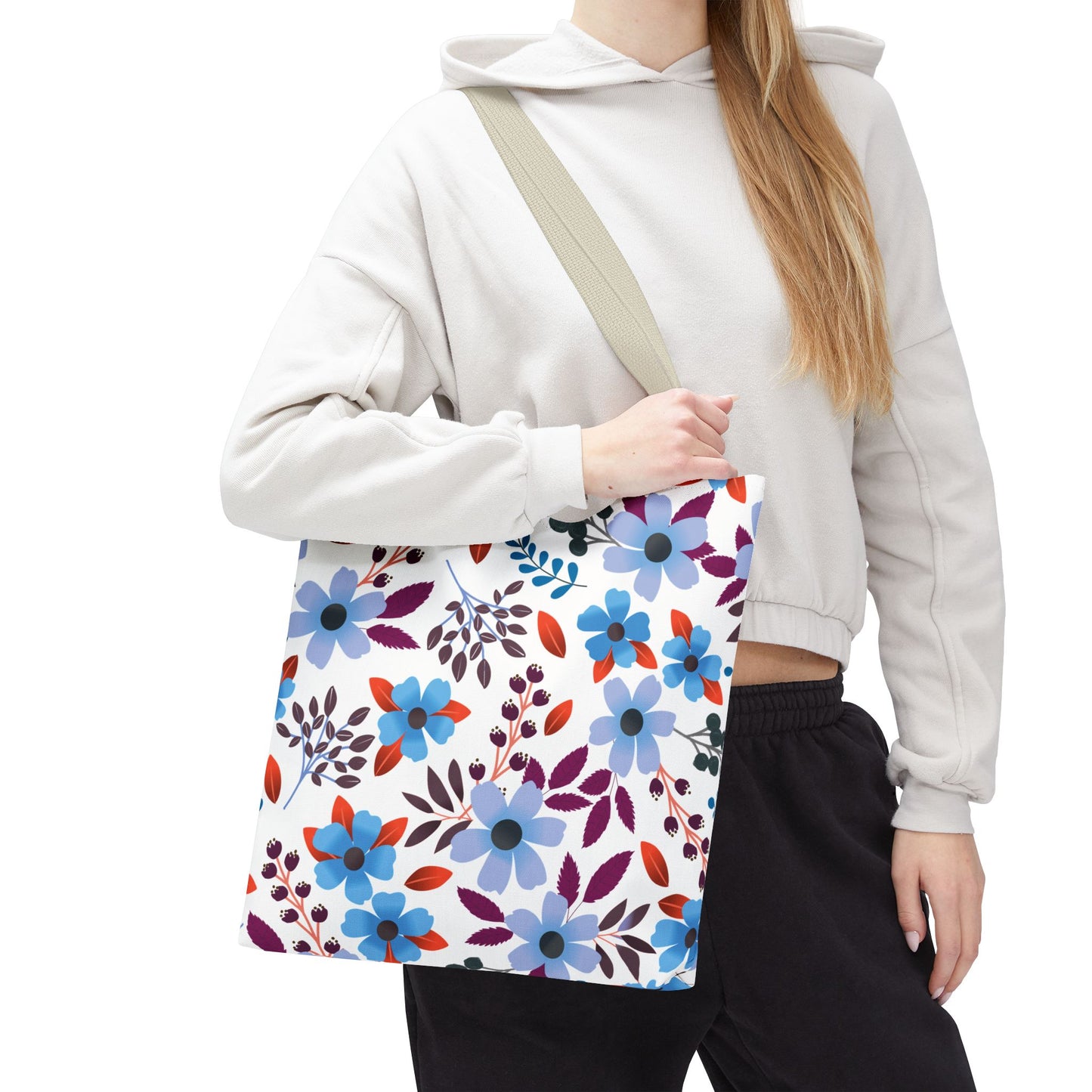 The Floral Tote Bag, featuring vibrant blue blossoms and berry clusters, is held over the shoulder, showcasing its spacious, durable design perfect for joyful summer outings and everyday use.