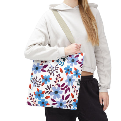The Floral Tote Bag, featuring vibrant blue blossoms and berry clusters, is held over the shoulder, showcasing its spacious, durable design perfect for joyful summer outings and everyday use.