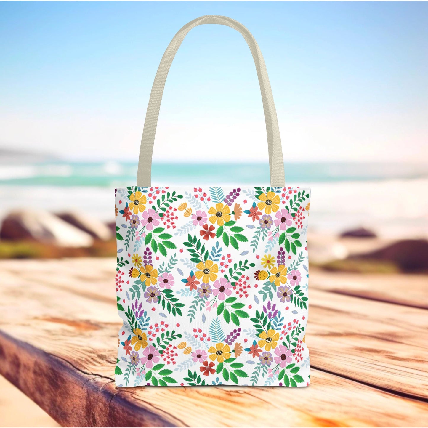 Floral Tote Bag with vibrant flowers and green leaves on a weathered wooden surface, featuring natural off-white handles, perfect for joyful summer outings, available in multiple sizes from FireBrook Designs.