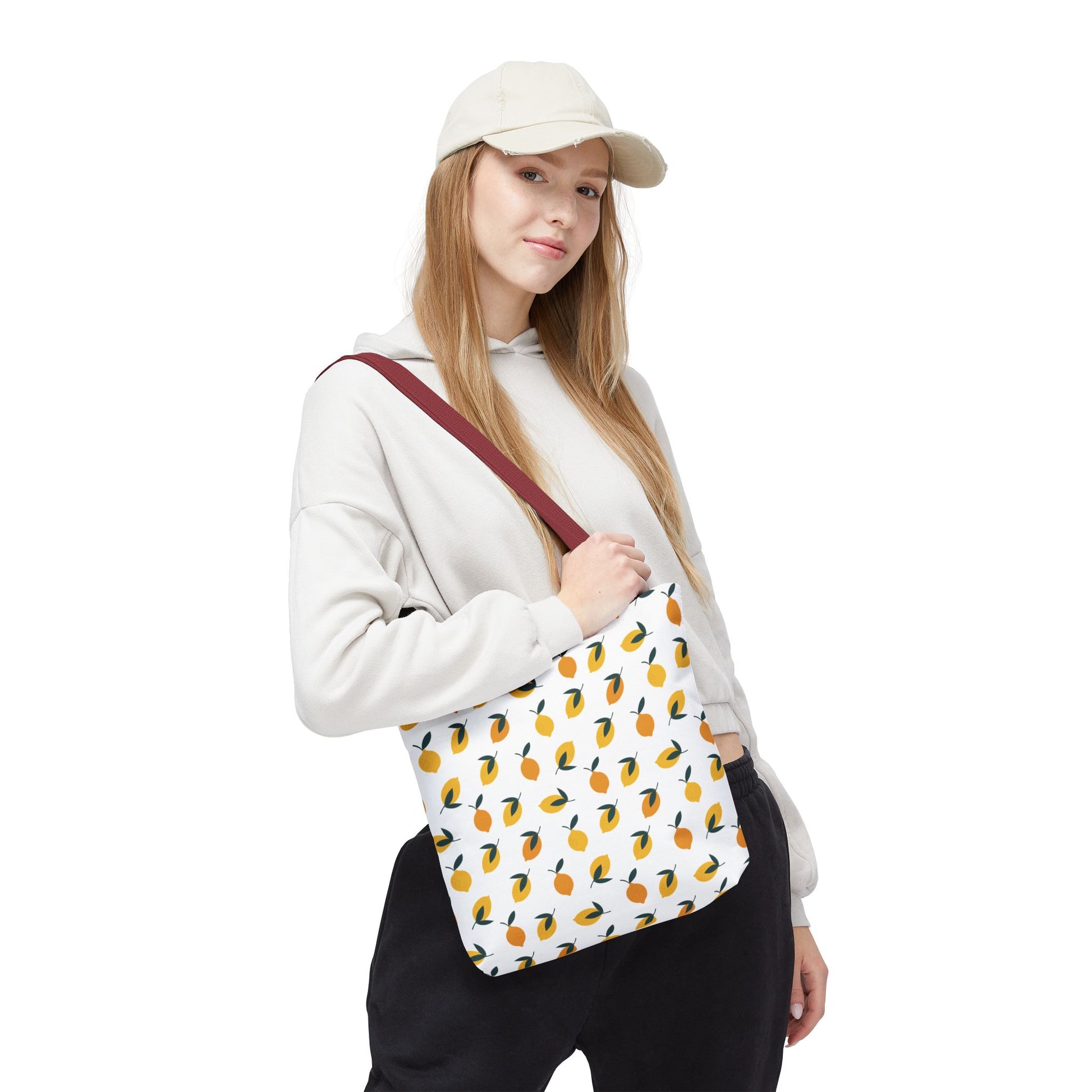 Lemon Drop Toss Tote Bag with vibrant lemon pattern, carried by a casually dressed woman. Perfect for summer outings, this durable canvas bag embodies FireBrook Designs' uplifting and joyful style.