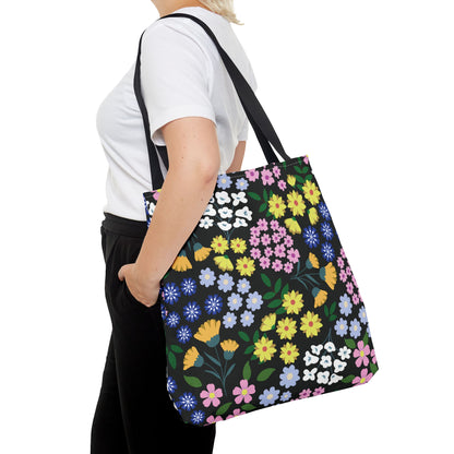 Person carrying a Floral Tote Bag featuring a vibrant floral pattern against a black backdrop, perfect for summer outings, showcasing FireBrook Designs' commitment to stylish, uplifting essentials.