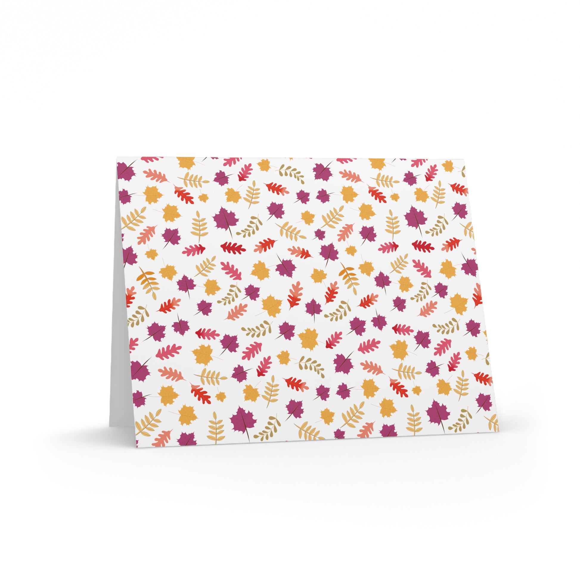 Autumn Greeting Cards — Pack of 8/16/24 featuring a vibrant pattern of stylized autumn leaves, propped open on a white surface, showcasing FireBrook Designs' commitment to uplifting, joyful stationery.
