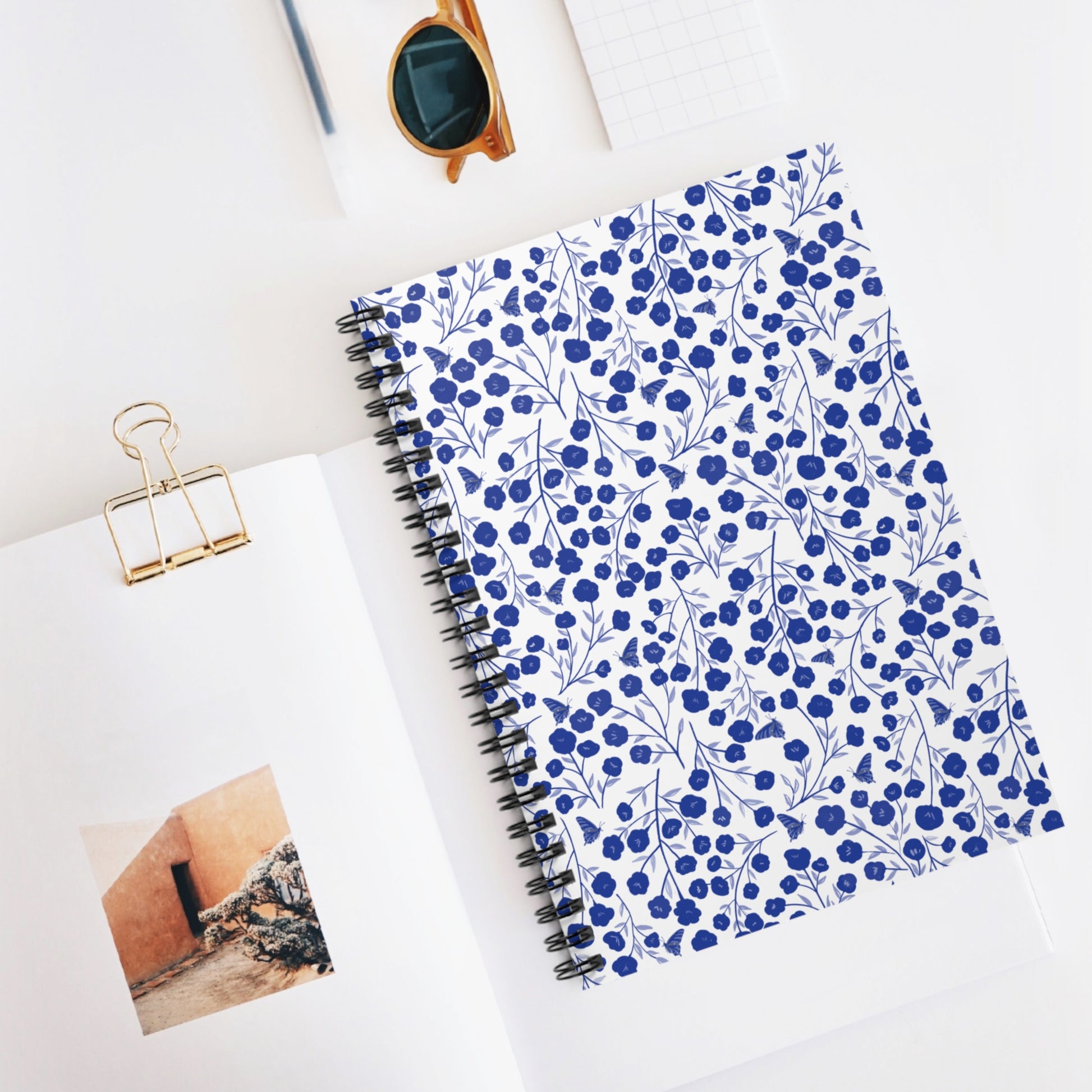 Floral Spiral Notebook features a vibrant blue floral pattern on a white cover, styled for creativity and organization. Perfectly paired with stylish stationery, inspiring joyful note-taking.