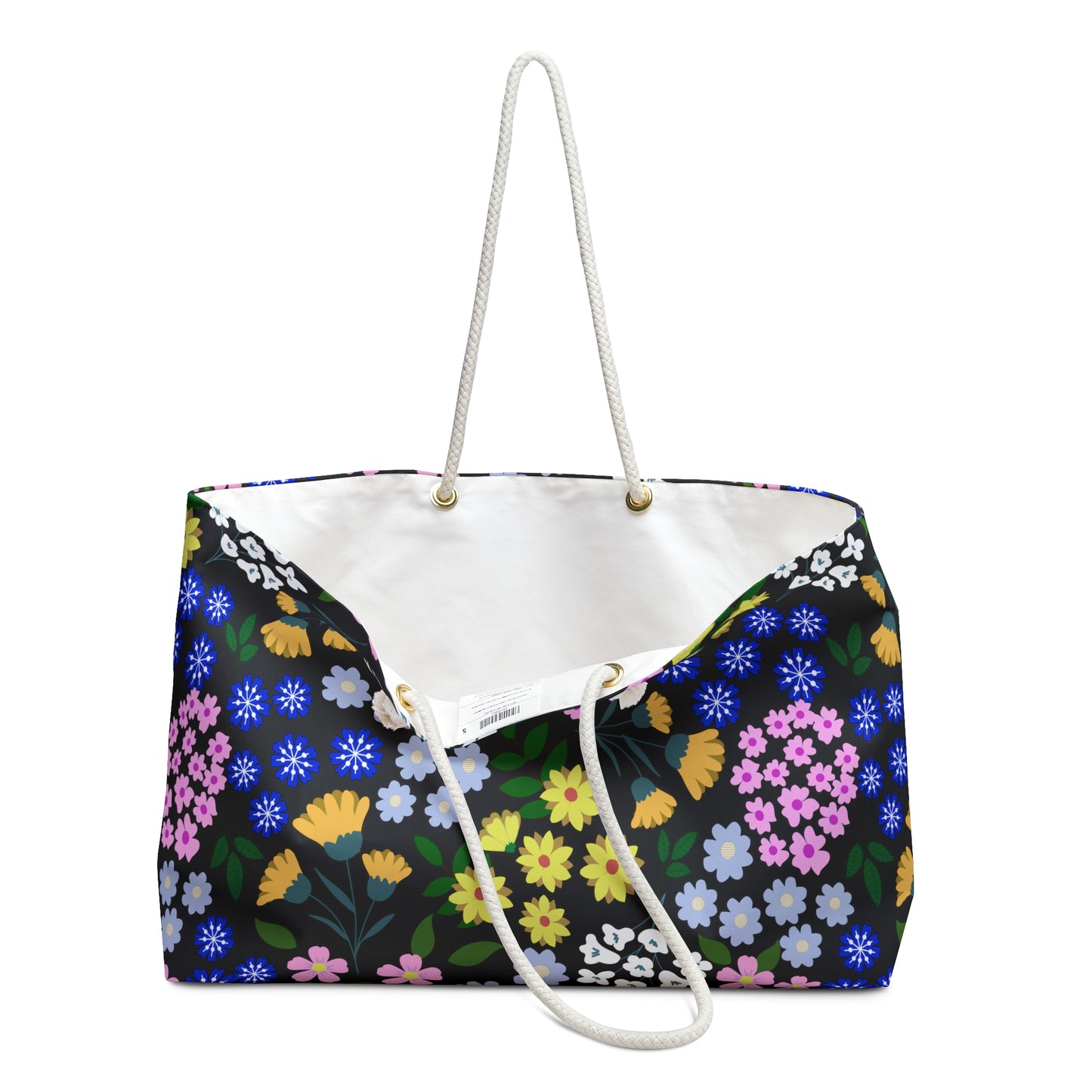 Weekender Bag with multicolor floral pattern on black, featuring white braided rope handles through gold grommets. Spacious, stylish design with cream interior, perfect for joyful travels.