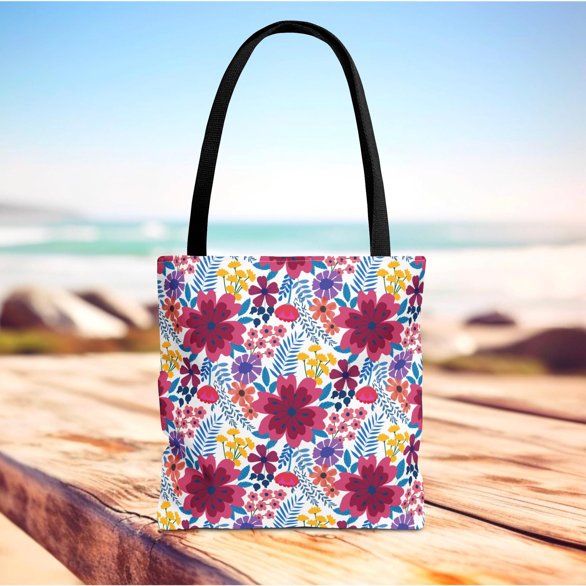 Floral Tote Bag featuring vibrant magenta, purple, and yellow flowers with blue foliage, designed for summer outings. Black straps, durable polyester, and reinforced stitching reflect FireBrook Essentials' commitment to style and functionality.