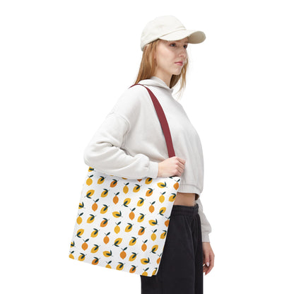 A person carries the Lemon Drop Toss Tote Bag featuring a lively lemon pattern and dark-red strap, perfectly embodying FireBrook Designs' vibrant and joyful style, ideal for summer outings.