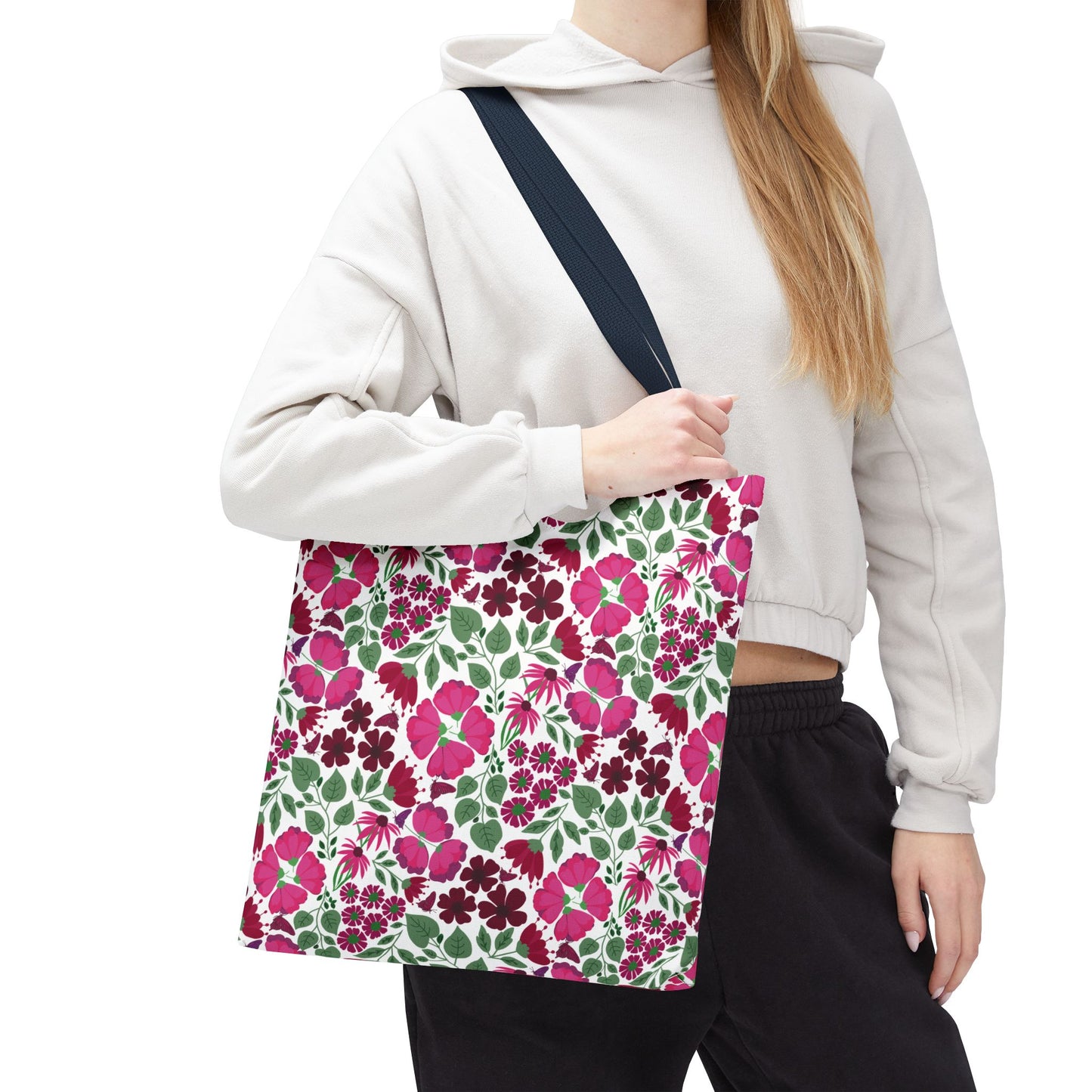 A person holds the Pink Lady Tote Bag, showcasing its vibrant floral pattern of pink and magenta flowers with green leaves, perfectly complementing any outfit while embodying FireBrook Designs' uplifting and stylish essence.