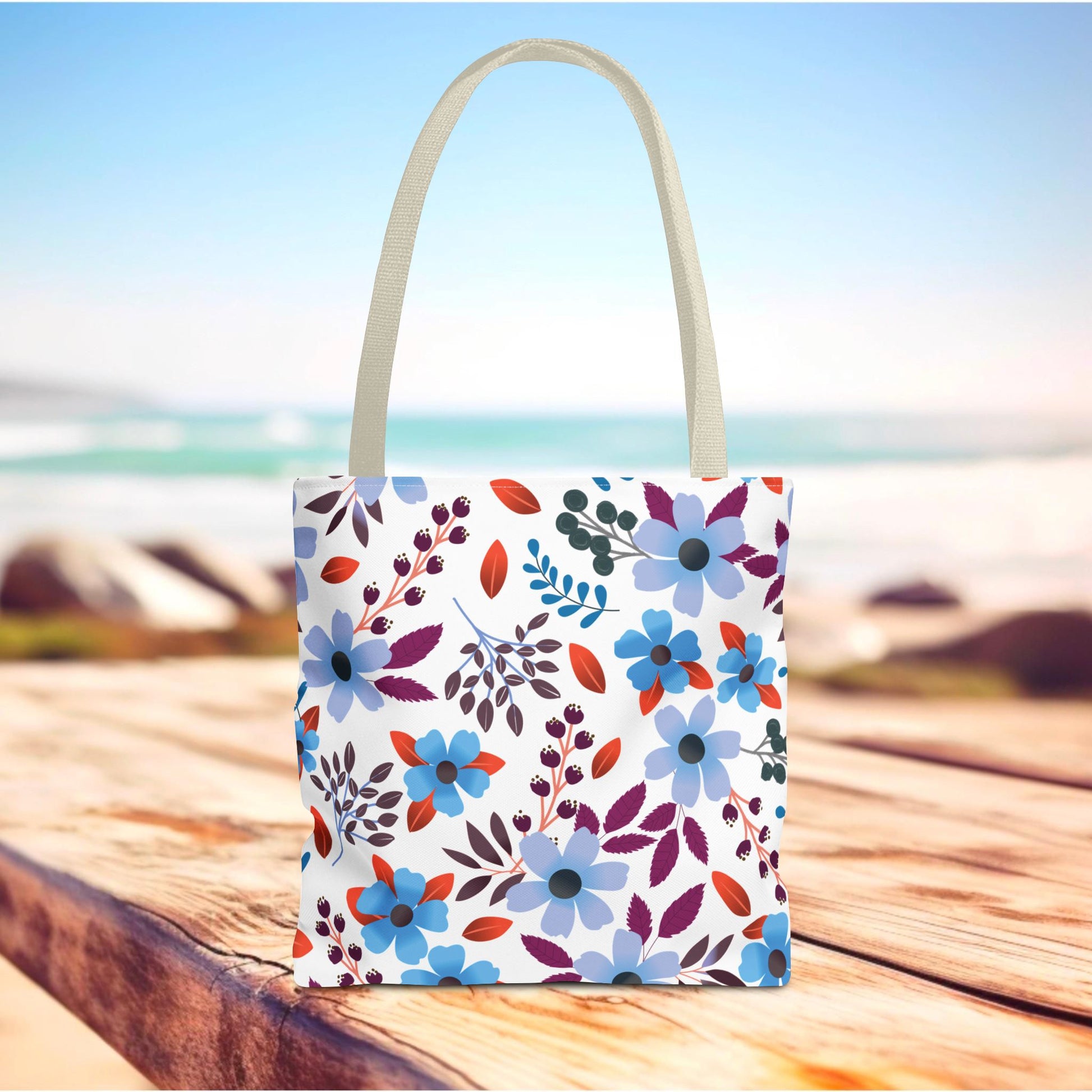 Floral Tote Bag on a wooden surface, featuring a vibrant blue, purple, and red floral pattern. Ideal for summer outings, highlighting the joyful, uplifting essence of FireBrook Designs.