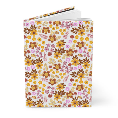 HARDCOVER JOURNAL, MATTE, RULED, 5X7, SEWN BIND, CLEAN-TEAR PAGES – RETRO BLOOM features a floral-patterned cover, slightly open, showcasing its blank pages, exemplifying FireBrook Designs' blend of style and functionality.