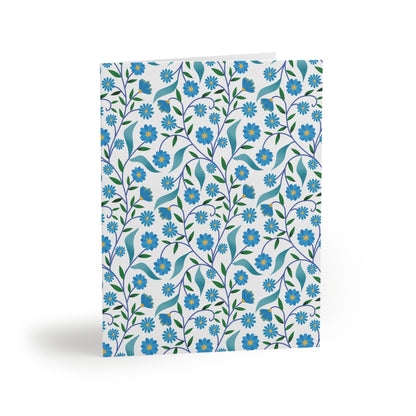 Floral Greeting Cards — Pack of 8/16/24, featuring a vibrant, stylized floral pattern of blue flowers and green leaves on a white background, folded, showcasing cheerful, garden-inspired design for heartfelt messages.