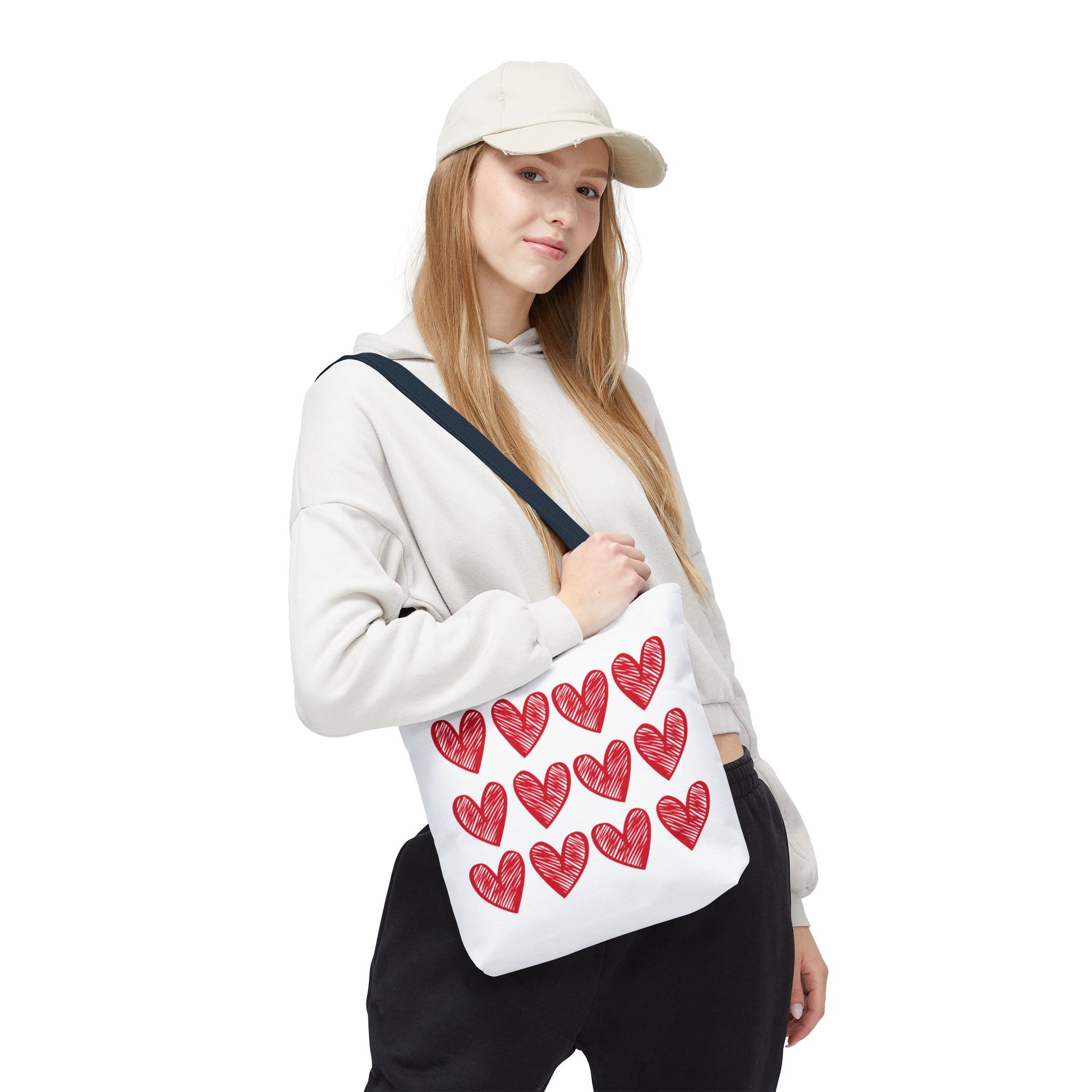 Hearts Tote Bag held by a woman, featuring a vibrant design with red hearts. This durable fashion accessory by FireBrook Designs adds a joyful touch to everyday outfits, perfect for quirky style enthusiasts.