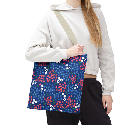 Floral Tote Bag featuring a navy-blue background with scattered red and white flowers, carried by a person. Designed by FireBrook Essentials, perfect for summer outings with durable polyester and reinforced handles.