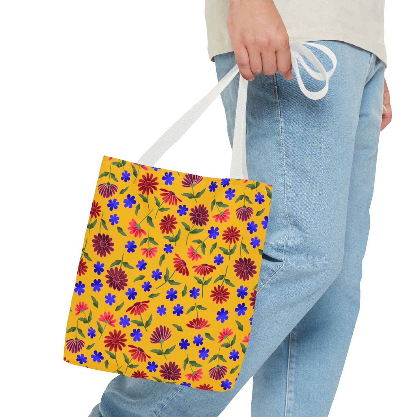 Golden Wildflower Tote Bag featuring vibrant red daisies and blue blossoms on a golden-yellow canvas. Held by white handles, its lively floral pattern embodies FireBrook Designs' joyful, practical style for everyday use.