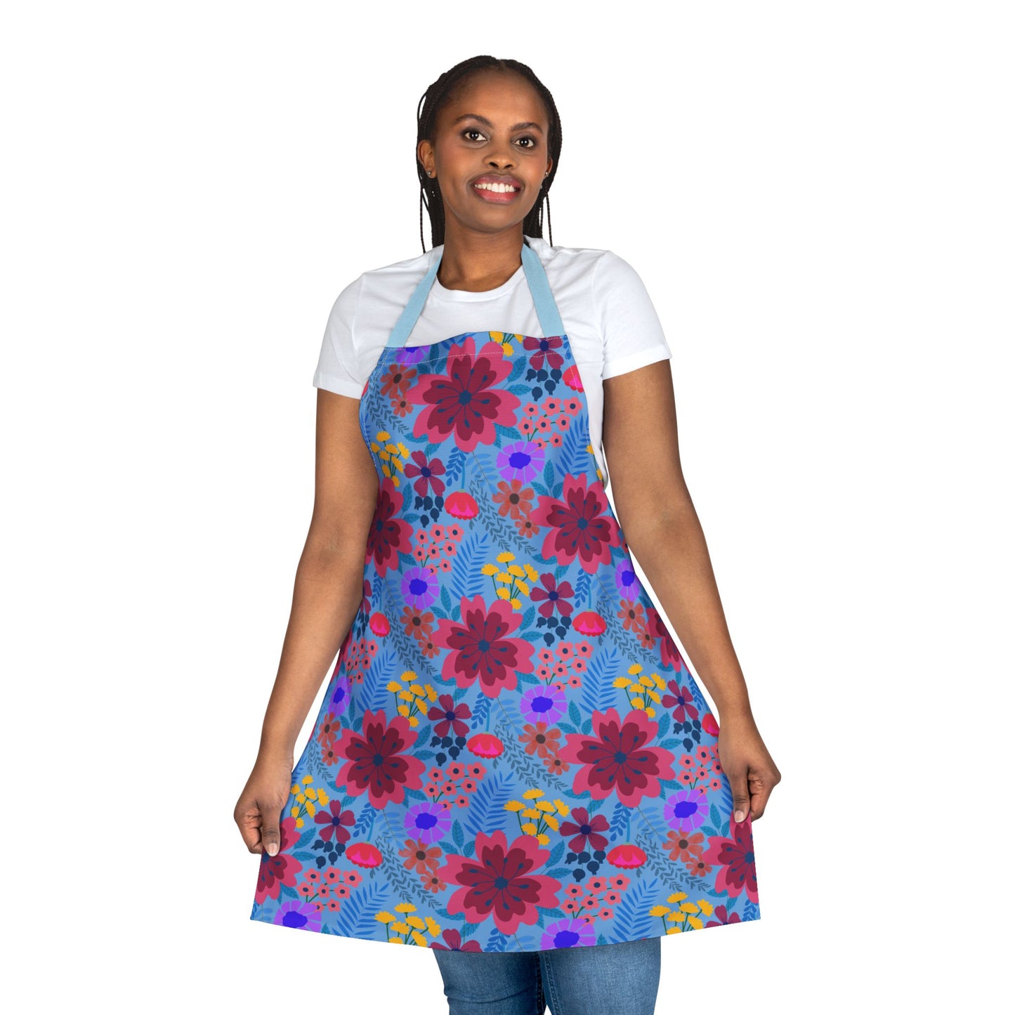 Woman models FireBrook Designs' Floral Apron with vibrant blooms, showcasing its stain-free polyester canvas ideal for various activities. She wears it comfortably over casual jeans, holding the apron’s hem.