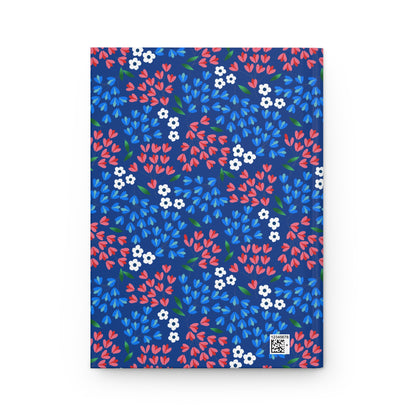 HARDCOVER JOURNAL, MATTE, RULED, 5X7, SEWN BIND, CLEAN-TEAR PAGES – WILDFLOWER SKY features a vibrant floral print on navy, with coral-red, sky-blue, and white blossoms, and green leaves, exuding elegance and positivity.