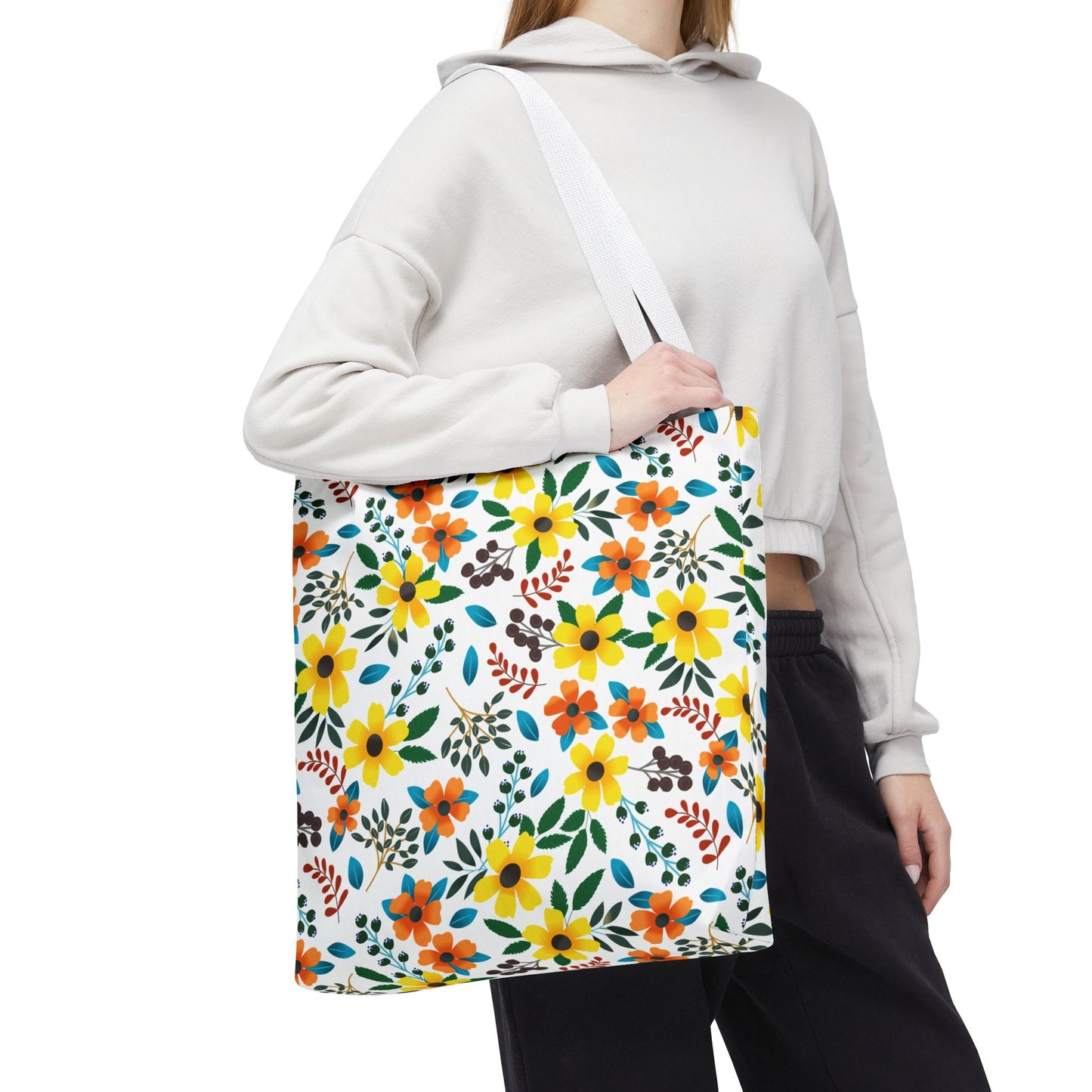 A person models the Sunny Meadow Mix Tote Bag, featuring vibrant yellow and orange daisies on a white background, perfect for summer outings, embodying FireBrook Designs' cheerful and uplifting aesthetic.