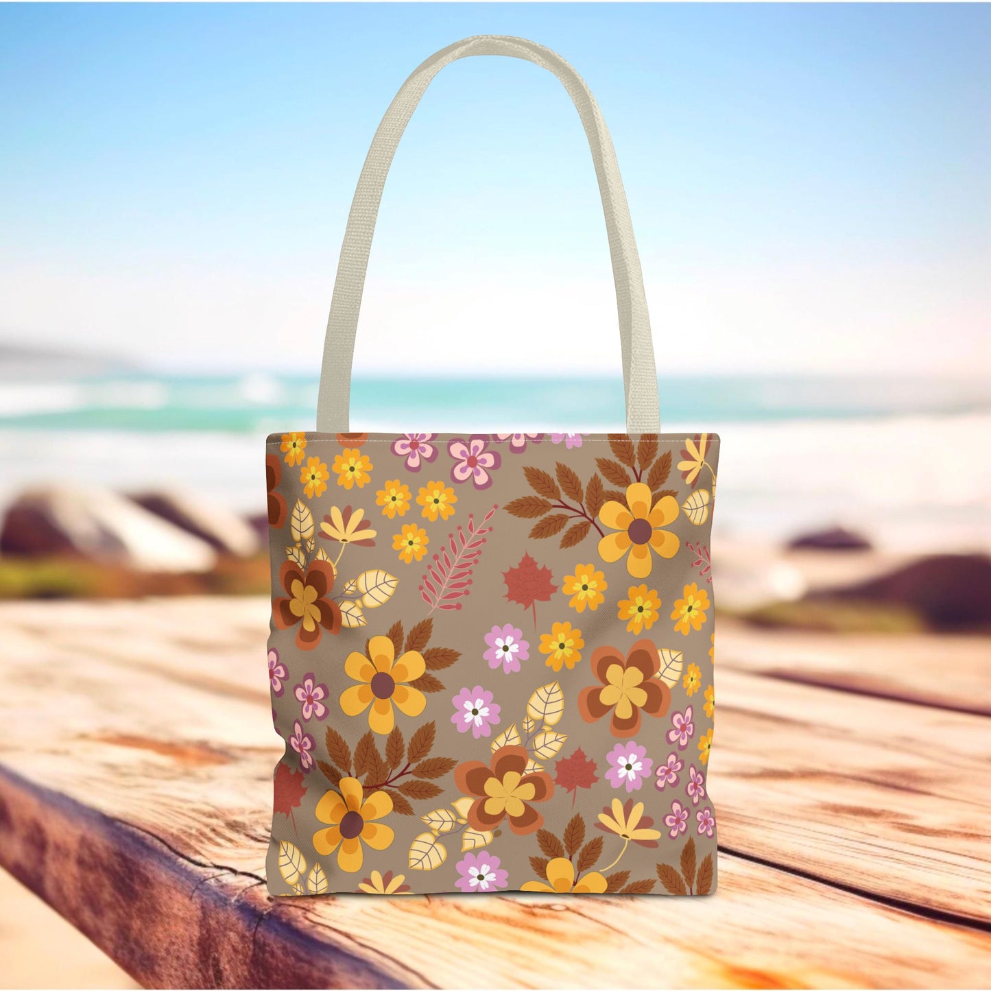 Harvest Brown Bloom Tote Bag on wooden surface, features a warm floral pattern with mustard, orange, and lavender hues. Natural handles, perfect for beach trips or market visits, embody FireBrook Essentials' joyful design ethos.