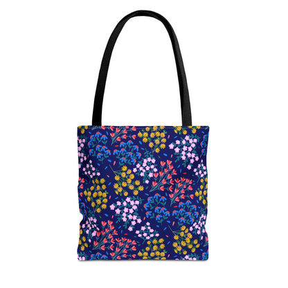 Midnight Garden Tote Bag features a dark navy-blue floral pattern with vibrant yellow, pink, red, and blue flowers. Equipped with sturdy black handles, it embodies FireBrook Designs' blend of style and practicality.