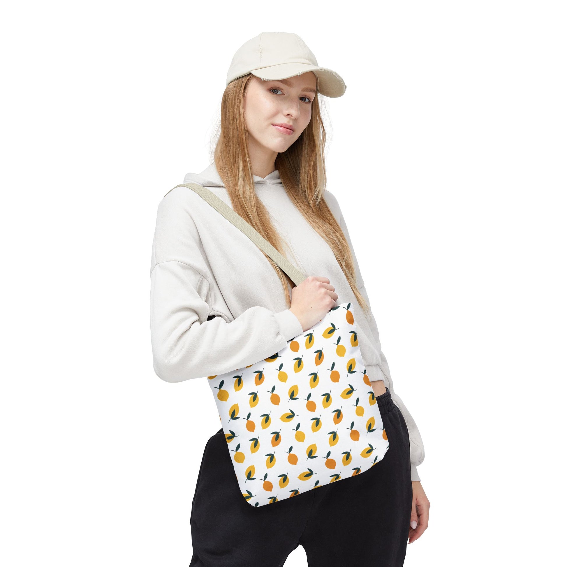 A young woman models the Lemon Drop Toss Tote Bag, featuring vibrant lemon and leaf patterns, ideal for summer outings. This stylish and cheerful bag complements her casual outfit with a refreshing touch.