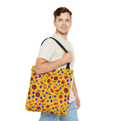 Young man casually carries the Golden Wildflower Tote Bag, featuring a mustard-yellow base with vibrant red and purple flowers, sturdy black straps, embodying FireBrook Designs' cheerful, practical style.