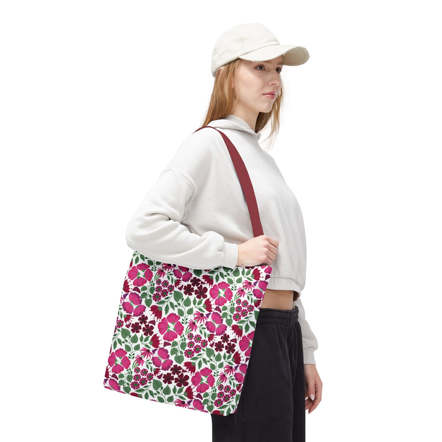 The Pink Lady Tote Bag, shown over a young woman's shoulder, features a vibrant pink, magenta, and red floral pattern, perfect for adding a cheerful touch to everyday outfits.