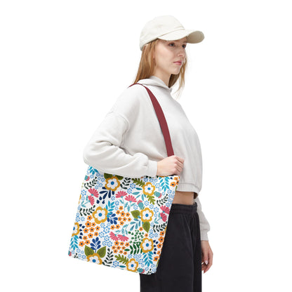 Floral Tote Bag with wide burgundy straps, showcasing vibrant blossoms, worn by a young person in casual attire. Perfect for summer outings, reflecting FireBrook Designs' uplifting and joyful style.