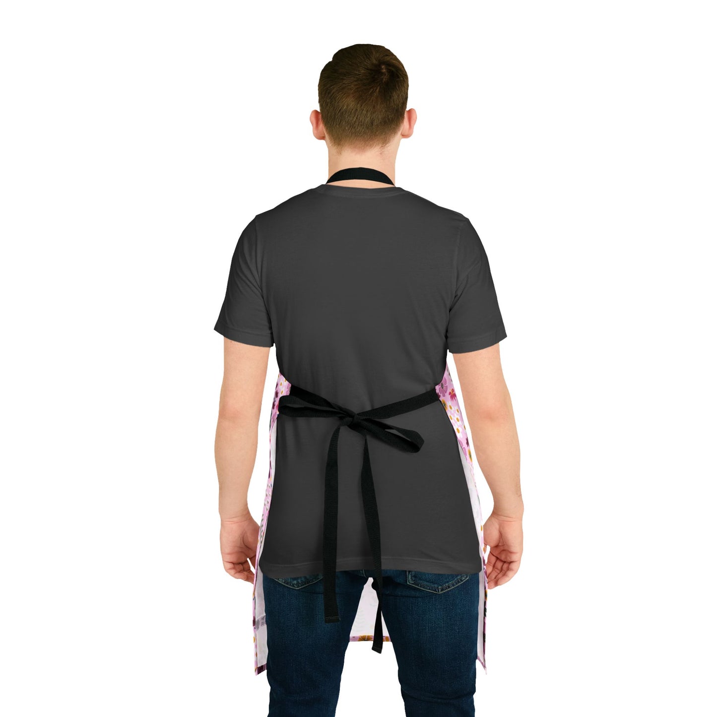 Person wearing a Floral Apron in pink with side patterns and black tie-back straps over a dark T-shirt and jeans, emphasizing comfort and style. Ideal for cooking or crafting.