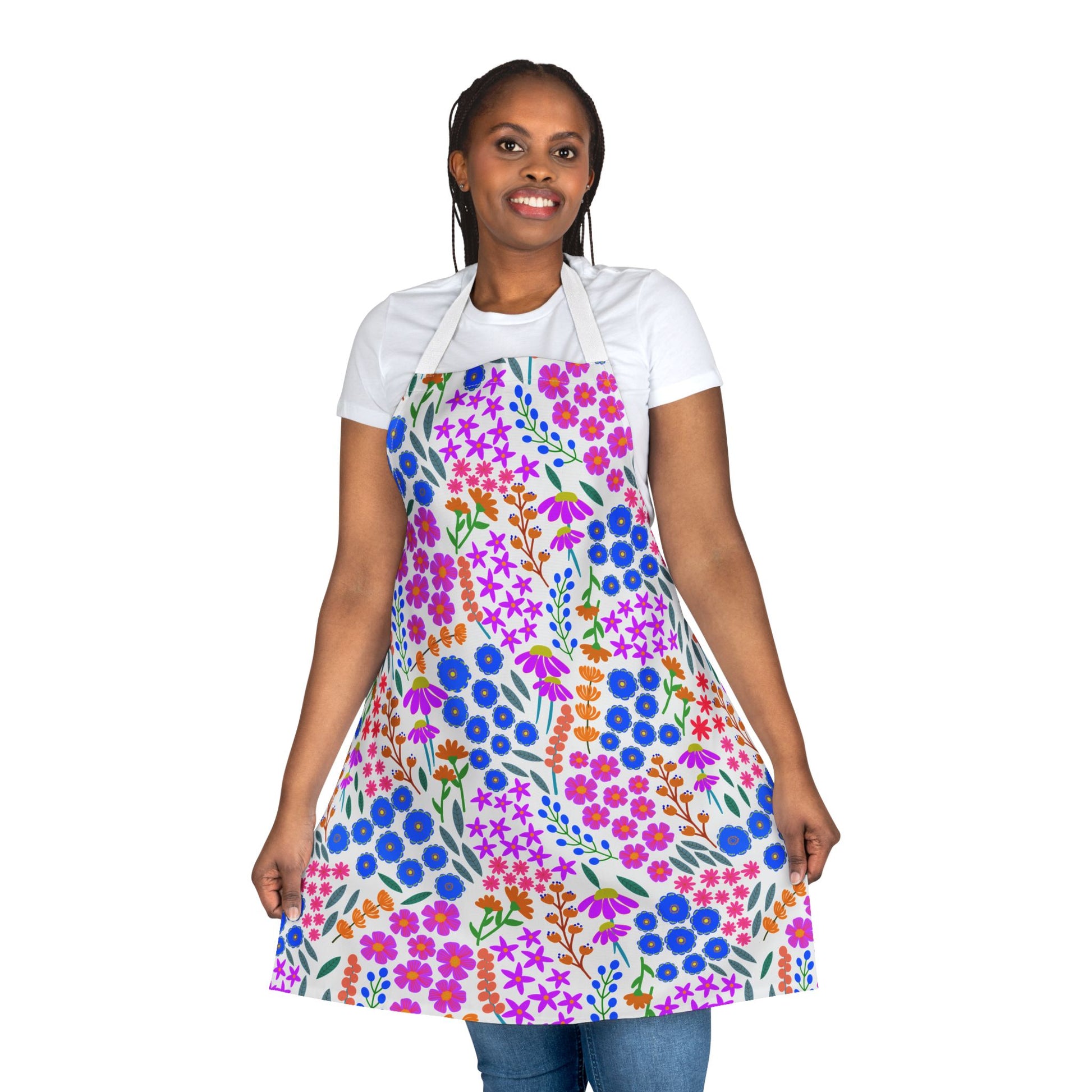 Person wearing a Floral Apron from FireBrook Designs, featuring a vibrant pattern of blossoms over a white T-shirt and jeans. This stain-free, full-coverage apron offers comfort and style for any activity.