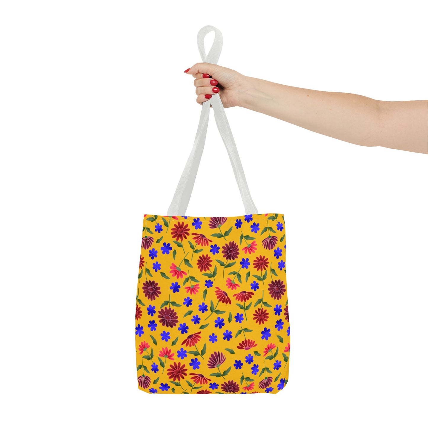 Golden Wildflower Tote Bag with a vibrant floral pattern, featuring blue and red blossoms on yellow. Held by white straps, this spacious and durable tote is perfect for cheerful, everyday use.