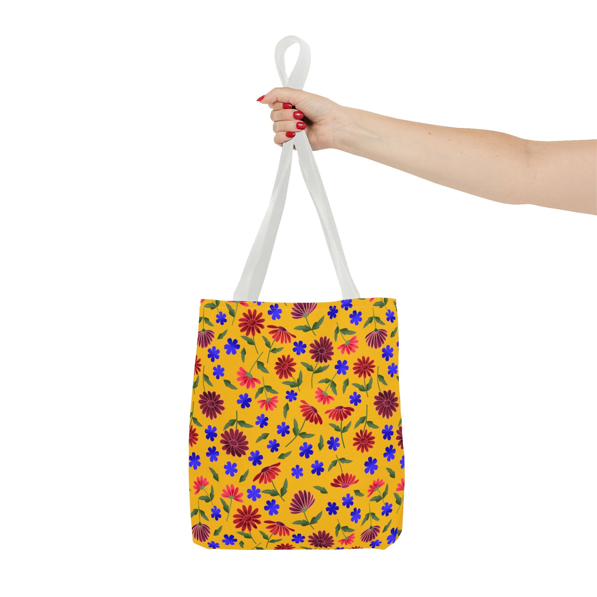 Golden Wildflower Tote Bag with a vibrant floral pattern, featuring blue and red blossoms on yellow. Held by white straps, this spacious and durable tote is perfect for cheerful, everyday use.