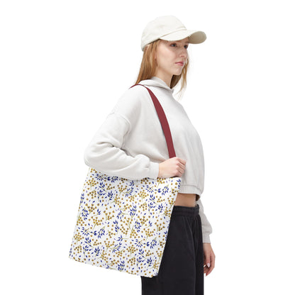 Young woman carries the Wild Herb Garden Tote Bag, featuring a white body with gold and blue botanical prints and a burgundy strap, ideal for summer activities.