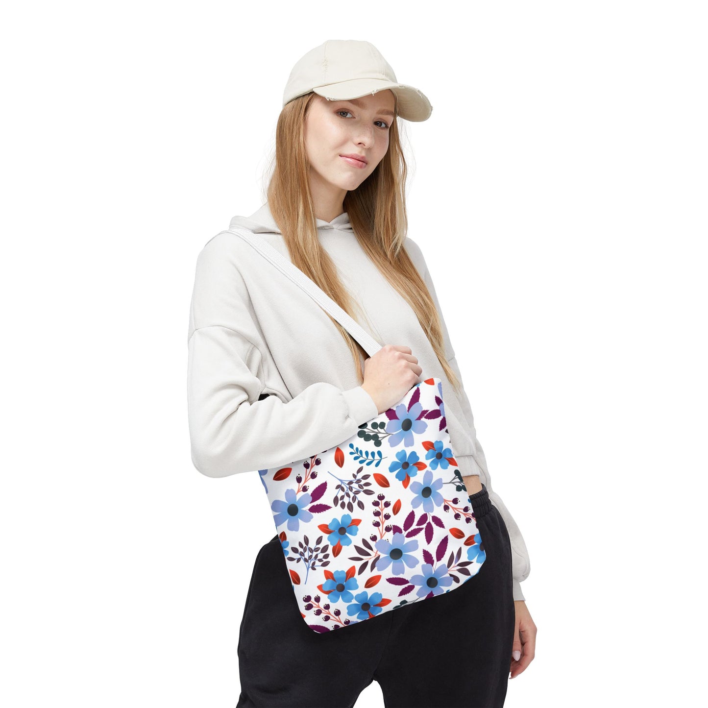 A young woman holds a Floral Tote Bag featuring blue, purple, and red flowers, embodying FireBrook Designs' cheerful style. Ideal for summer outings, this durable tote enhances joyful experiences.