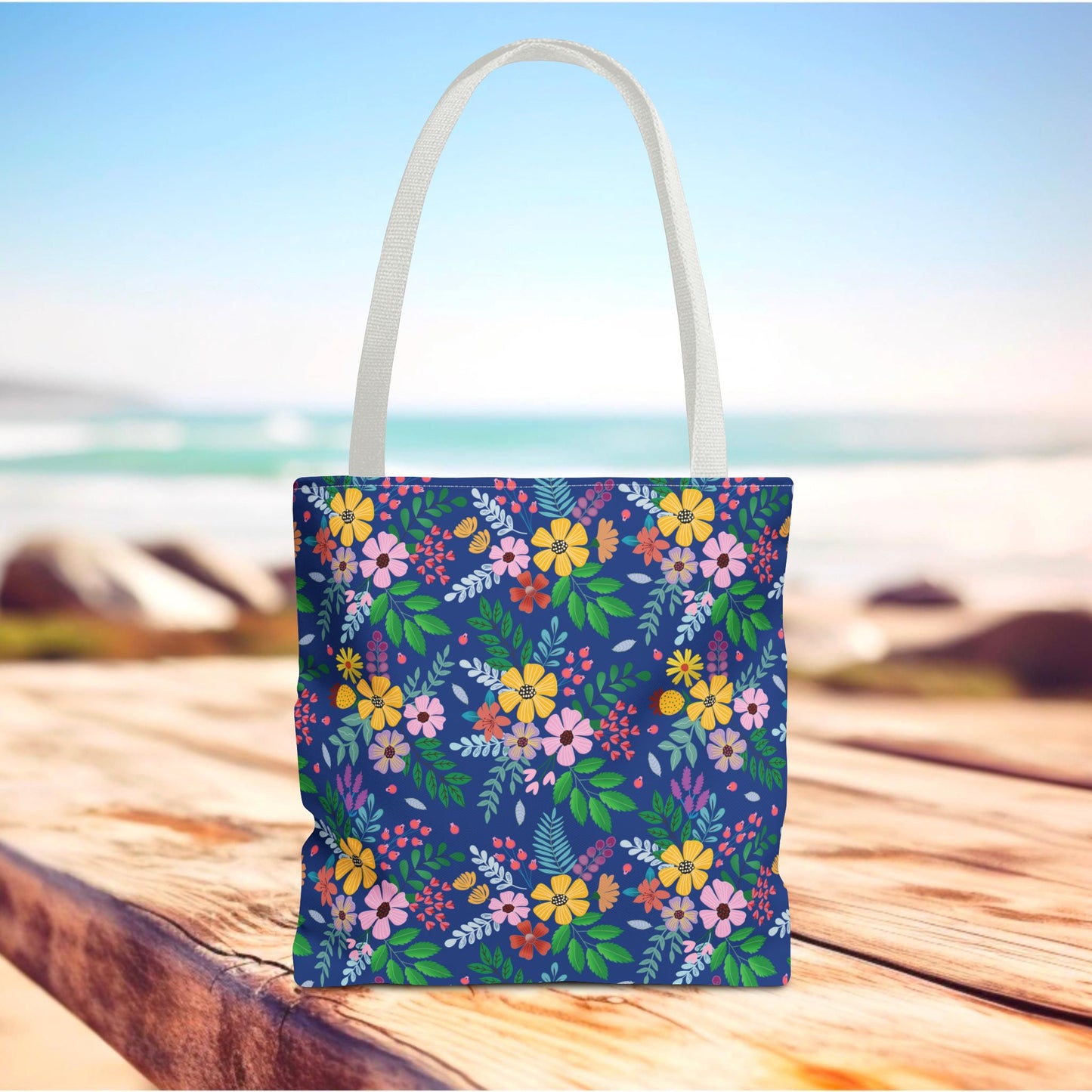 Floral Tote Bag with vibrant flowers and green leaves on a navy-blue background, featuring white handles. Perfect for summer outings, embodying FireBrook Designs' joyful and stylish essence.