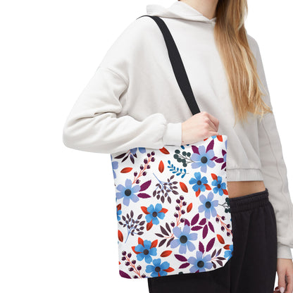 Person wearing a light-colored cropped hoodie holds a Floral Tote Bag with a vibrant blue, purple, and red floral pattern, ideal for summer outings, complementing FireBrook Designs' joyful and uplifting style.
