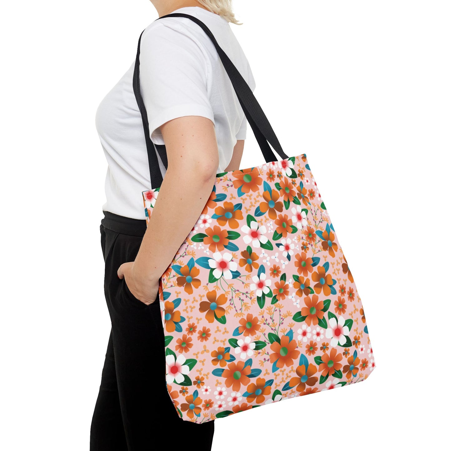 A person carries the Peach Poppy Grove Tote Bag, featuring a vibrant floral pattern on soft pink, over their shoulder. This stylish, durable bag complements joyful outings, embodying FireBrook Essentials' uplifting design ethos.