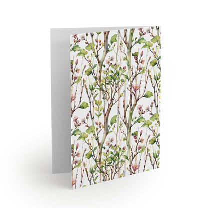 Greeting Cards — Pack of 8/16/24 featuring a watercolor-style botanical print with green leaves and pink blossoms on the front, folded open to reveal a blank interior, ideal for personalized messages.