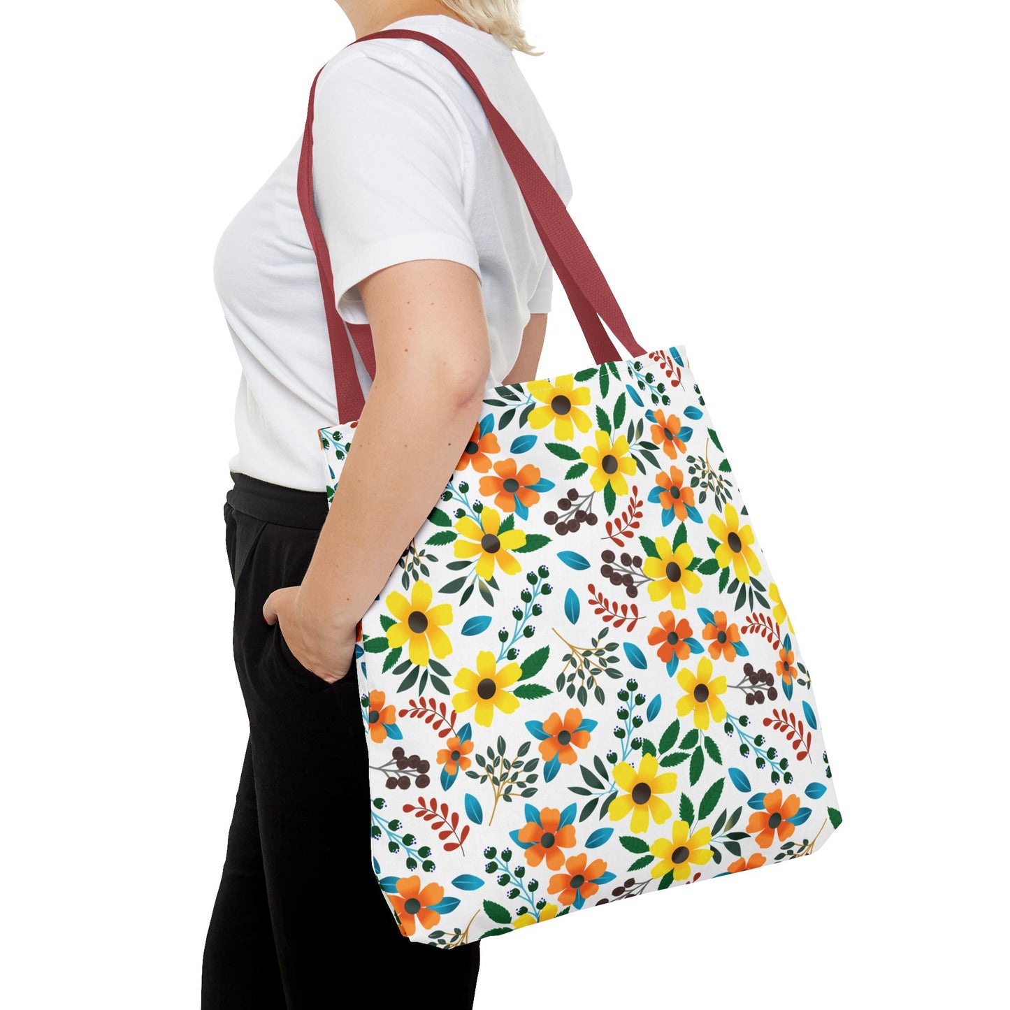 Person wearing a white T-shirt carries the Floral Tote Bag with burgundy/red straps and a vibrant floral print, exemplifying FireBrook Designs' cheerful, durable, and stylish approach to summer essentials.