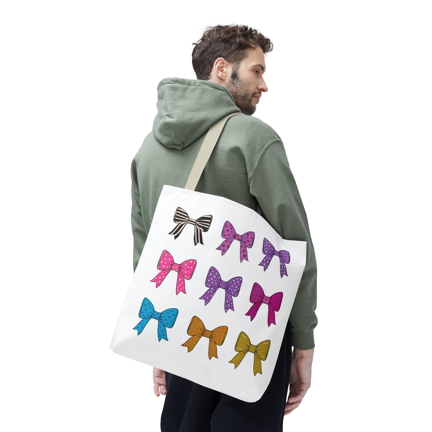 Man wearing green sweatshirt holding Bows Ribbons Tote Bag, featuring playful bow patterns, designed for style and practicality. Ideal for daily use with ample space.