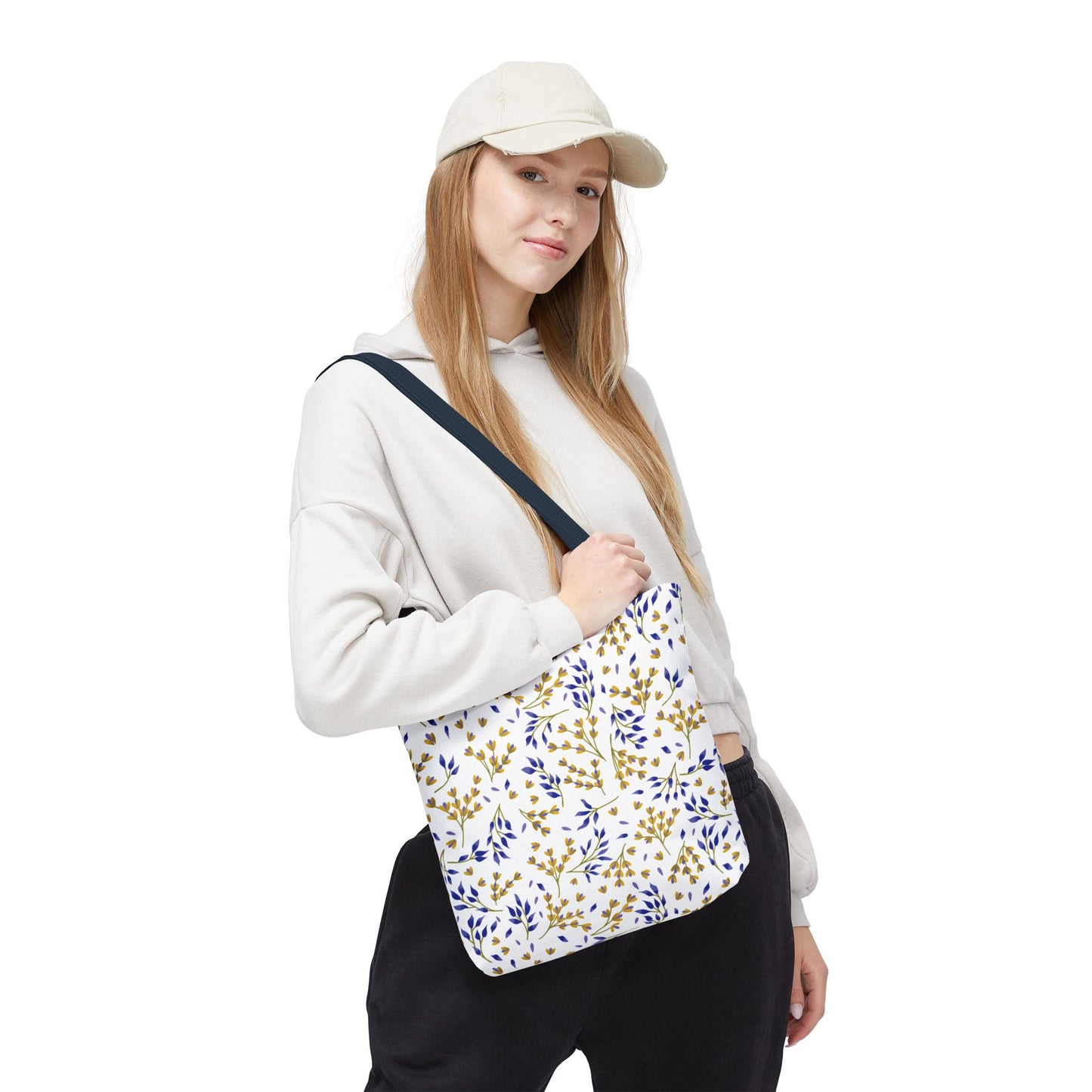 Floral Tote Bag slung over a casually dressed woman's shoulder, featuring a scattered leaf pattern in gold and blue tones, embodies stylish functionality for joyful summer outings, aligning with FireBrook Designs’ uplifting ethos.