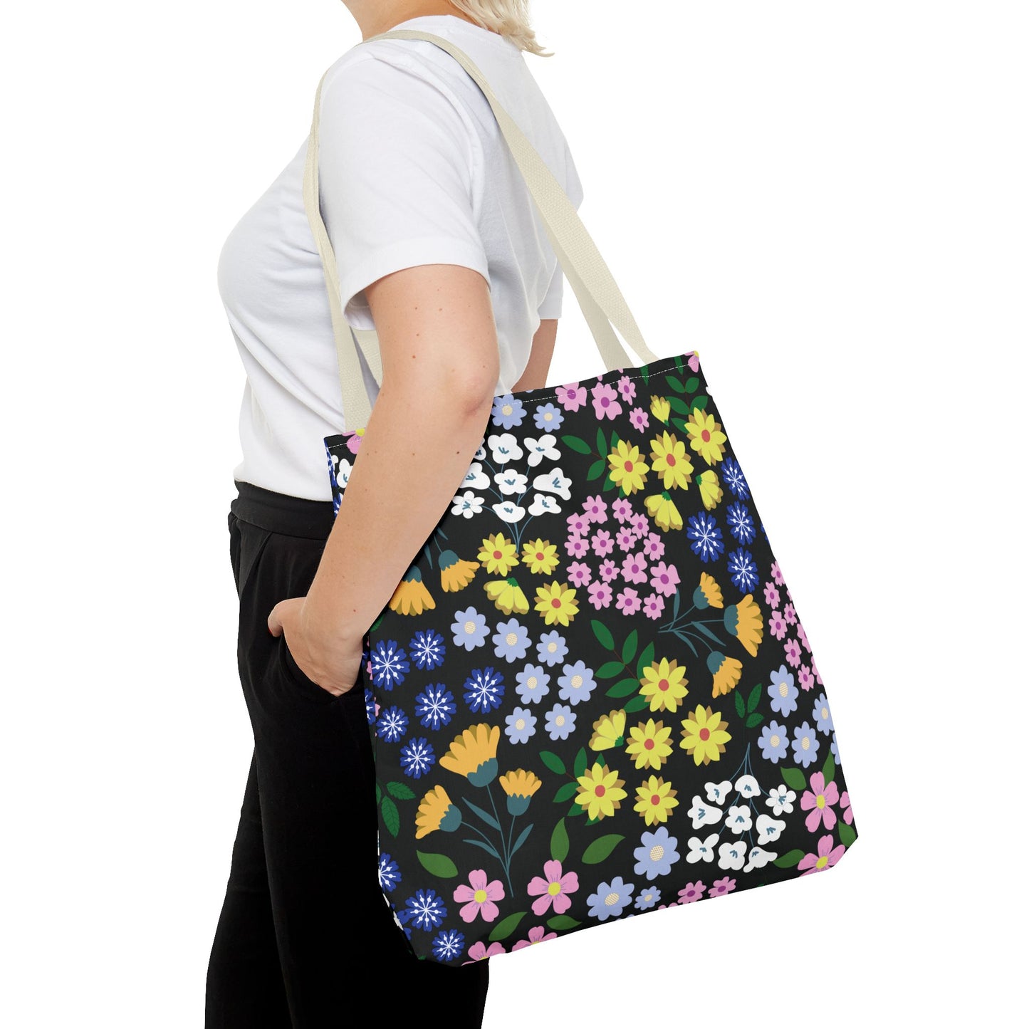 Floral Tote Bag with colorful flower patterns, carried by a person in casual attire. Ideal for cheerful outings, embodying FireBrook Designs' uplifting style. Durable polyester, cream straps, perfect for summer adventures.