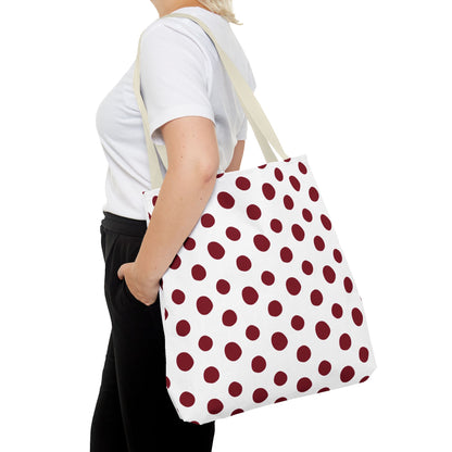 Woman holding the Burgundy Polka Dots Tote Bag, featuring a red and white polka dot design. Durable polyester fabric, ideal for everyday use. Perfect for adding a pop of color to your outfit.