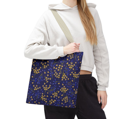 A person wears a light hoodie and dark pants, holding a Floral Tote Bag in deep navy with yellow and blue botanical patterns, embodying FireBrook Essentials' uplifting, stylish approach to daily accessories.
