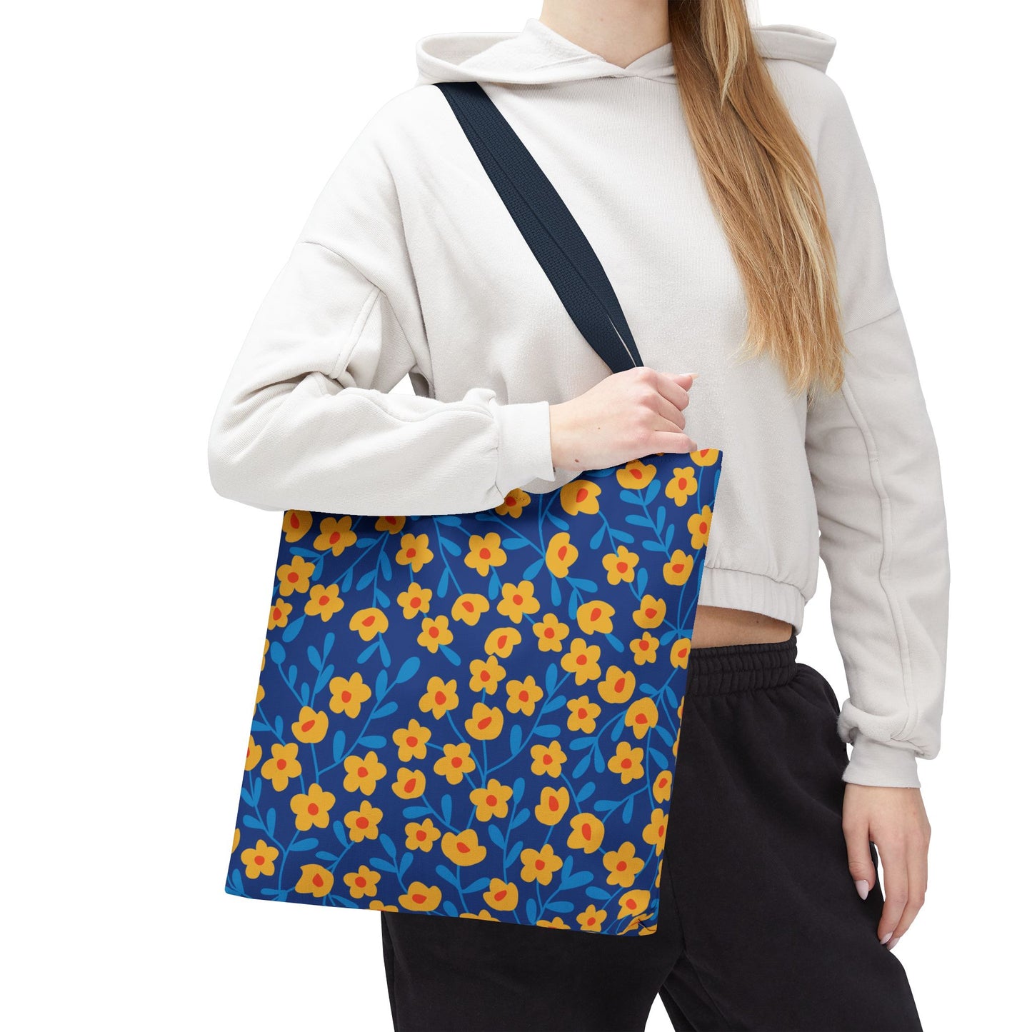 Cobalt Poppy Field Tote Bag featuring vibrant yellow-orange flowers and blue foliage on a deep blue backdrop, shown being carried casually, highlighting its spaciousness and cheerful design perfect for joyful outings.