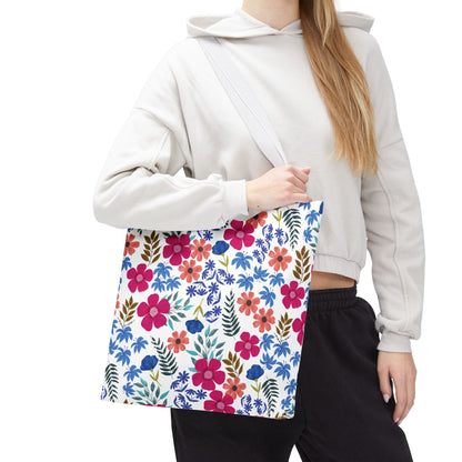 Floral Tote Bag featuring a vibrant floral print with pink, red, and blue blossoms, carried over the shoulder by a person in a light hoodie, perfect for brightening summer outings.