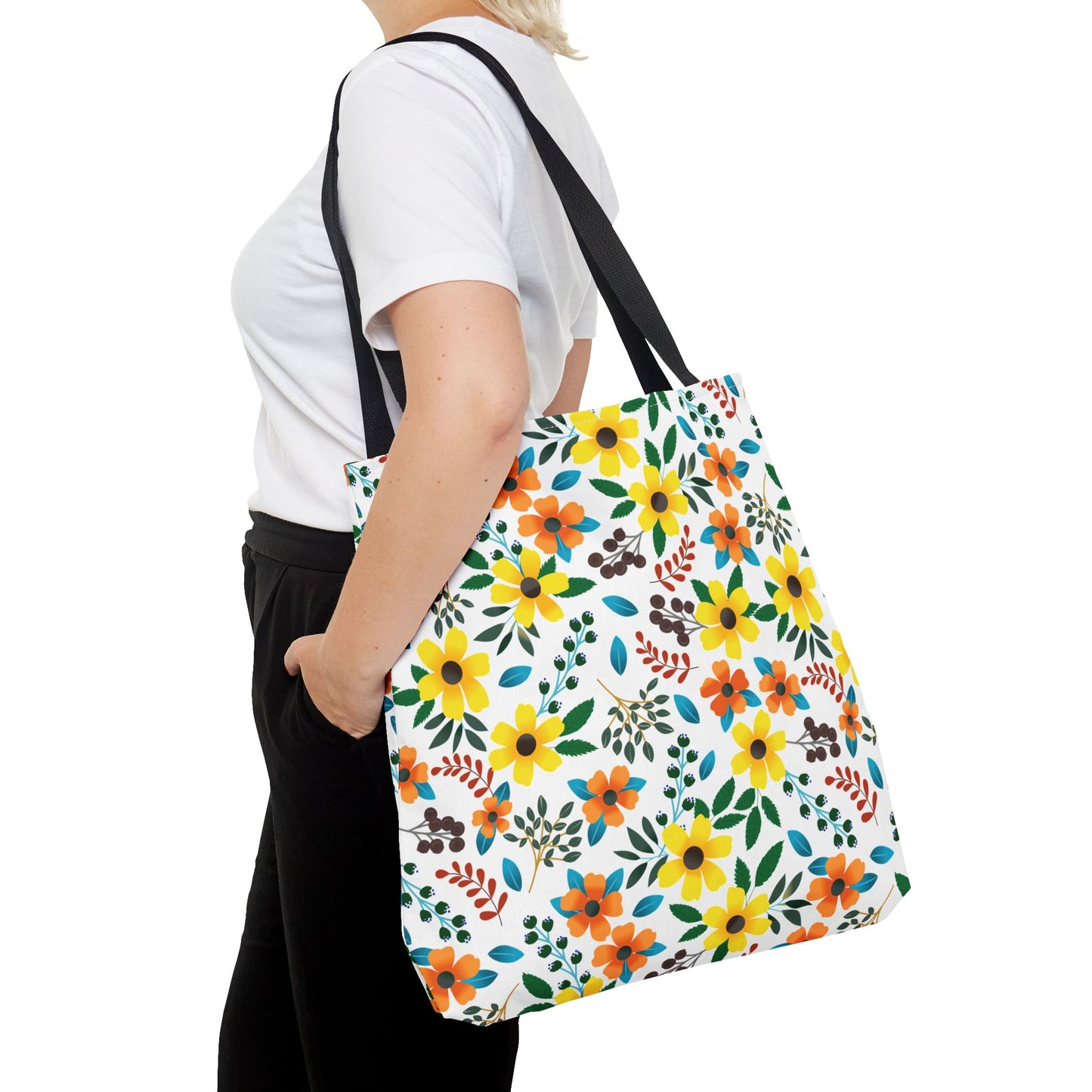 Person in profile wearing a plain white T-shirt and black pants carries a Floral Tote Bag with a bright multicolored floral pattern and black straps, showcasing FireBrook Designs' vibrant and joyful style.
