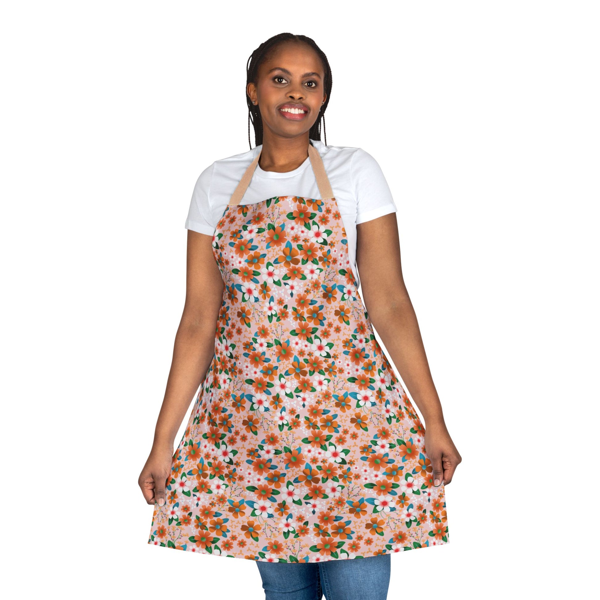 Woman wearing a Floral Apron with a vibrant orange, green, and white pattern, showcasing its full coverage. The apron features a tie-back closure and stain-free, comfortable design suitable for various activities.