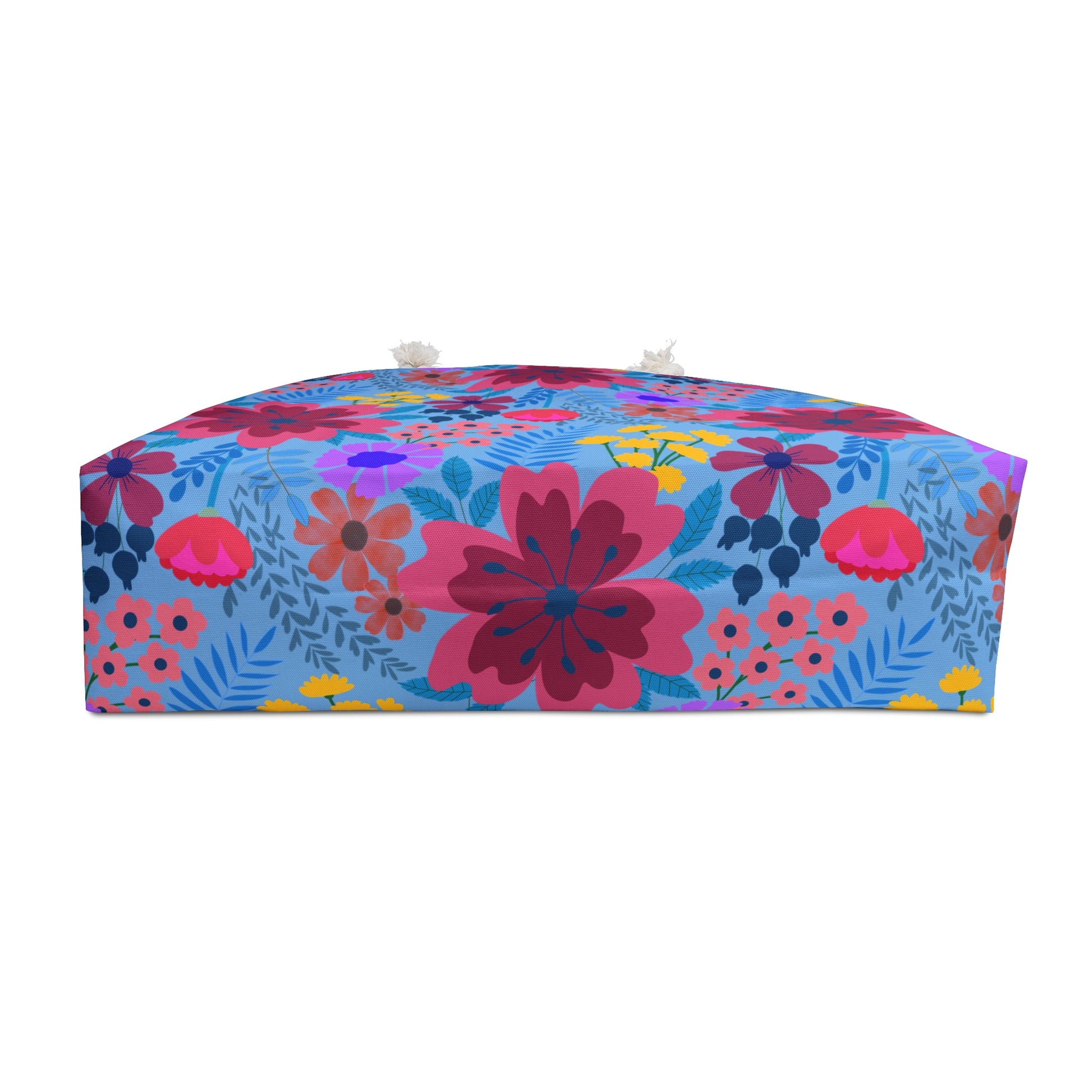 Weekender Bag: A vibrant blue pouf-style ottoman with a bold floral print, featuring two rope handles, embodies FireBrook Essentials' flair for stylish, uplifting designs.